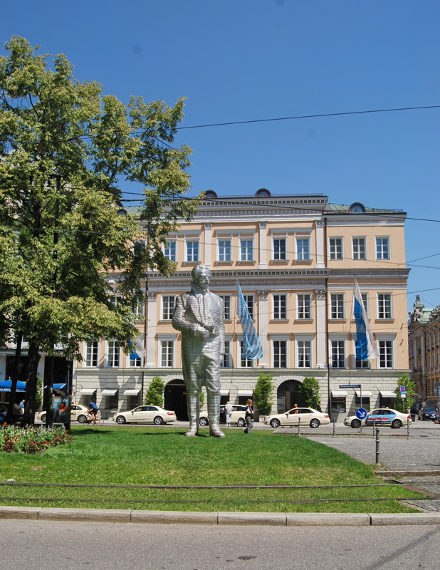 The striking, layered aluminum Sculpture of Maximilian Joseph Graf Von Montgelas by artist Karin Sander, standing on the Promenadeplatz in front of the historic Palais Montgelas in Munich